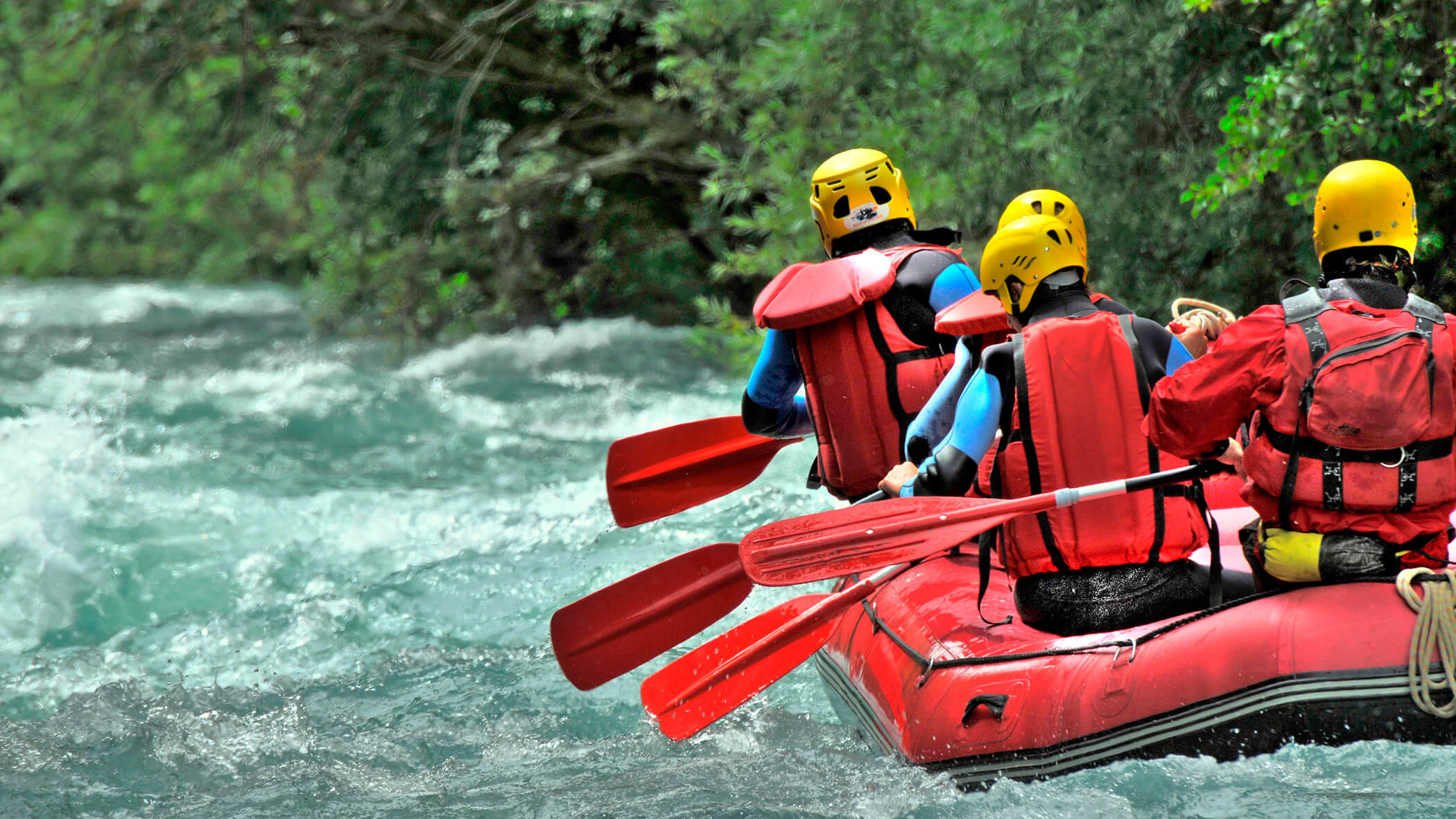 Eine Gruppe beim Rafting in einem roten Raftingboot - OLM Nature Escape