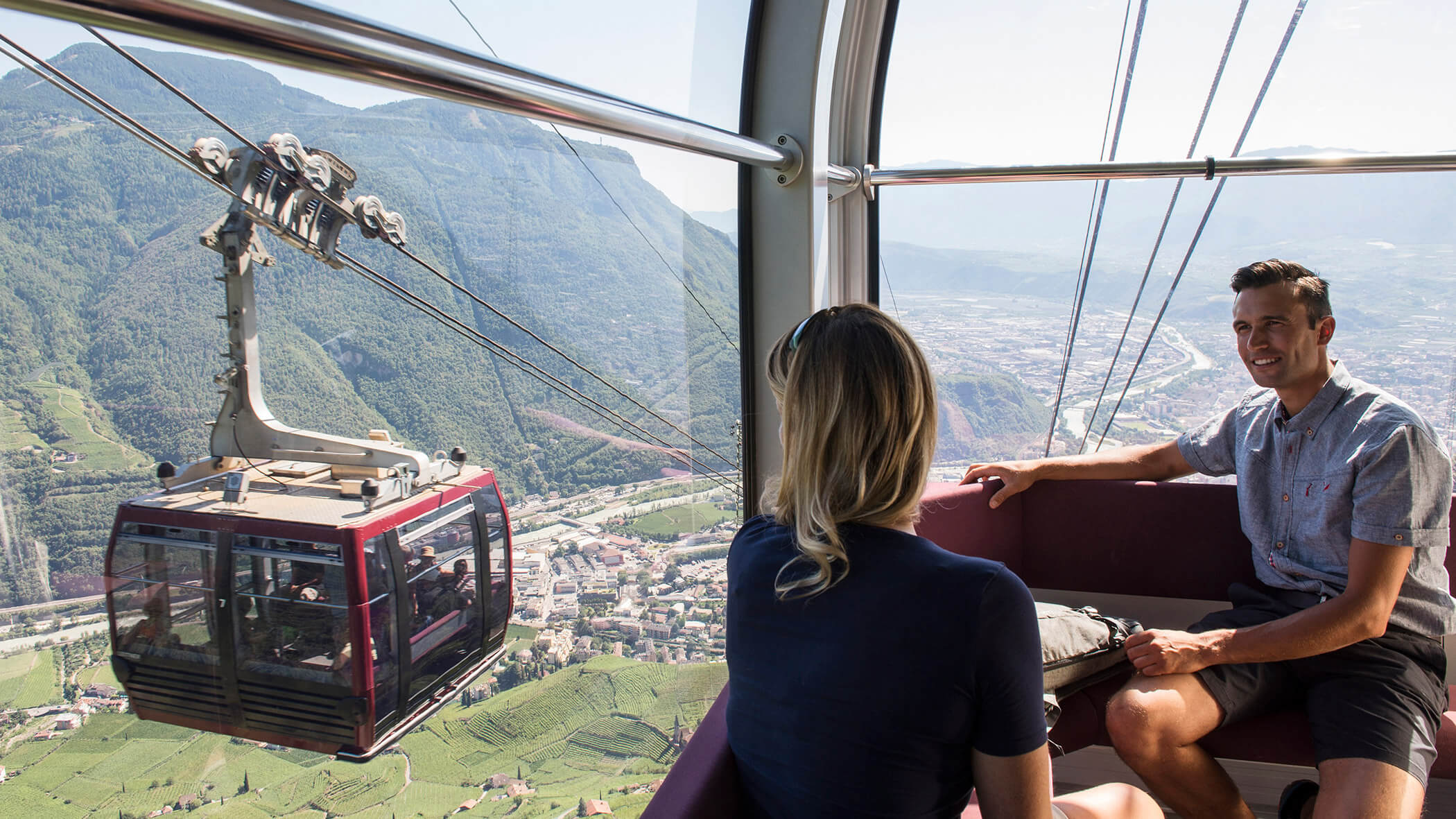 Ein Pärchen sitzt in der Gondel der Rittnerbahn und fährt talabwerts - OLM Nature Escape
