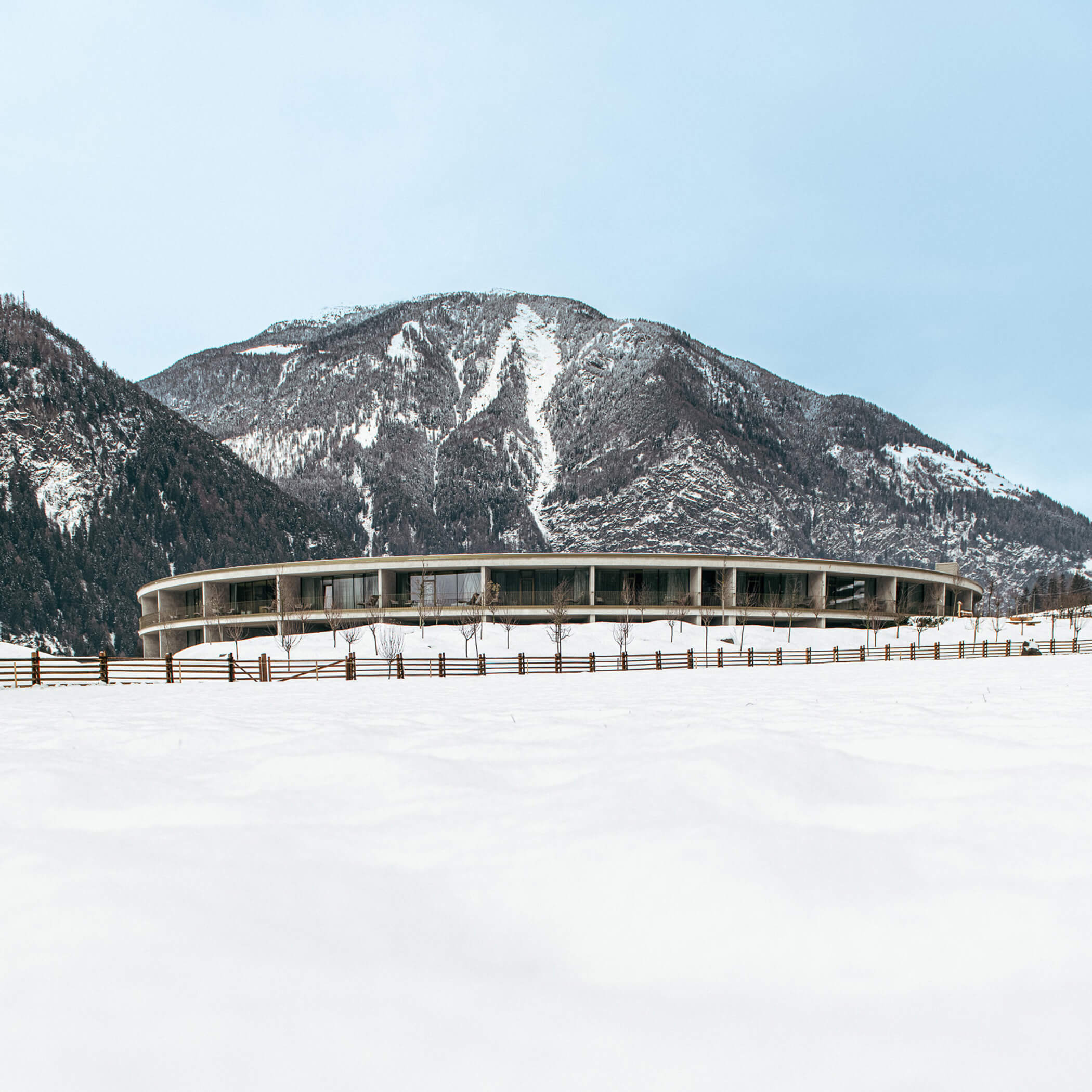 Aparthotel covered in snow with mountain peaks in the background - OLM Nature Escape
