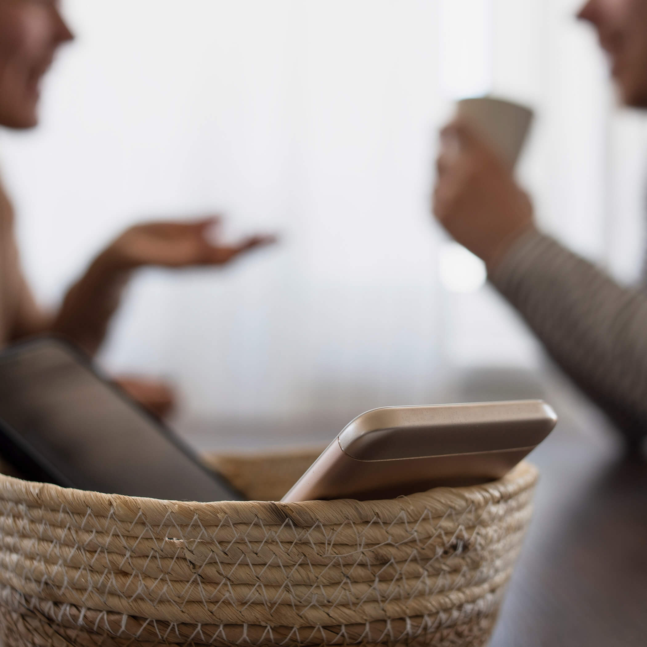 Urlaub ohne Handy - zwei Personen unterhalten sich während die Handys in einem Korb liegen - OLM Nature Escape