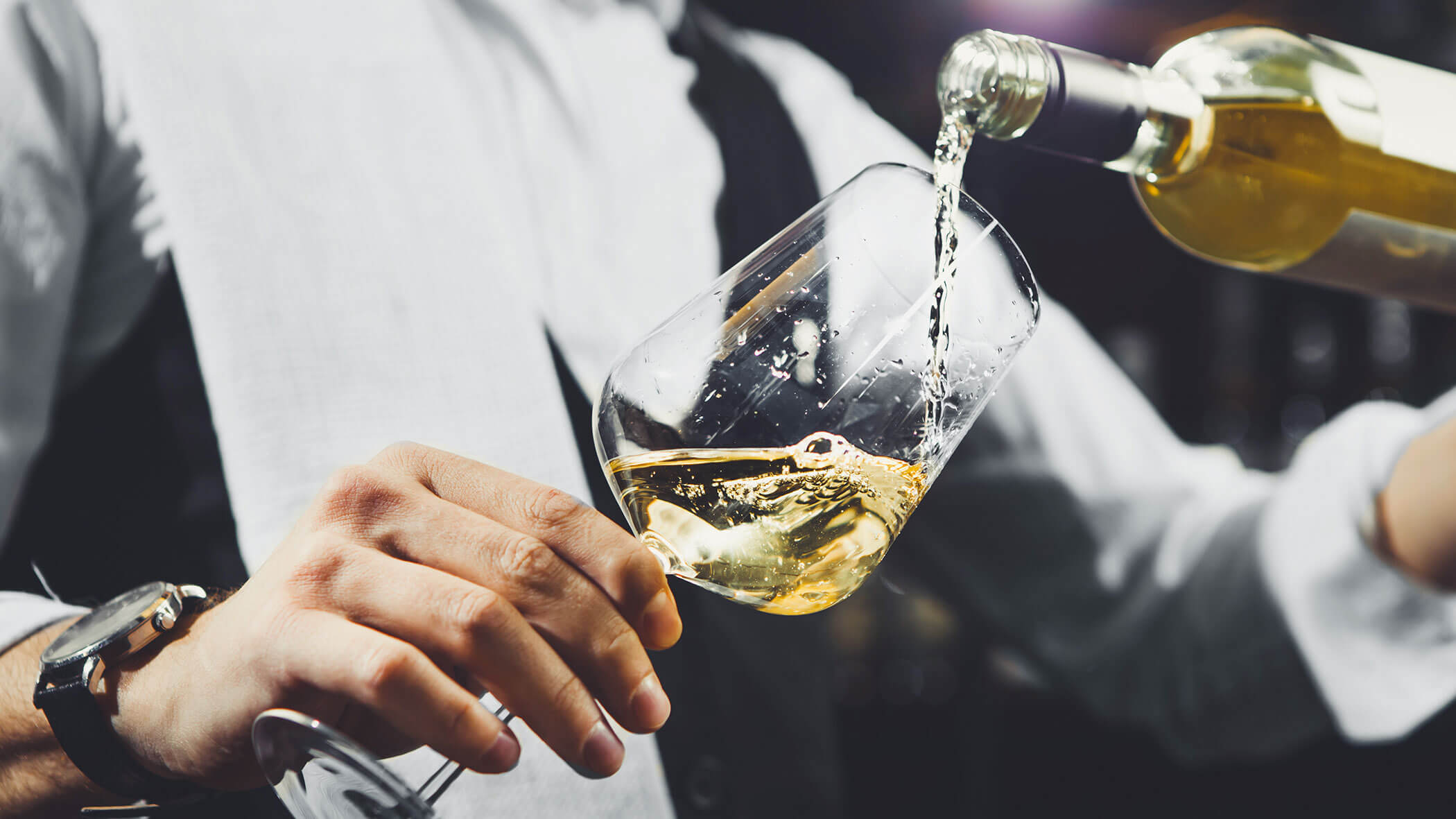 Un uomo versa del vino bianco in un bicchiere al 