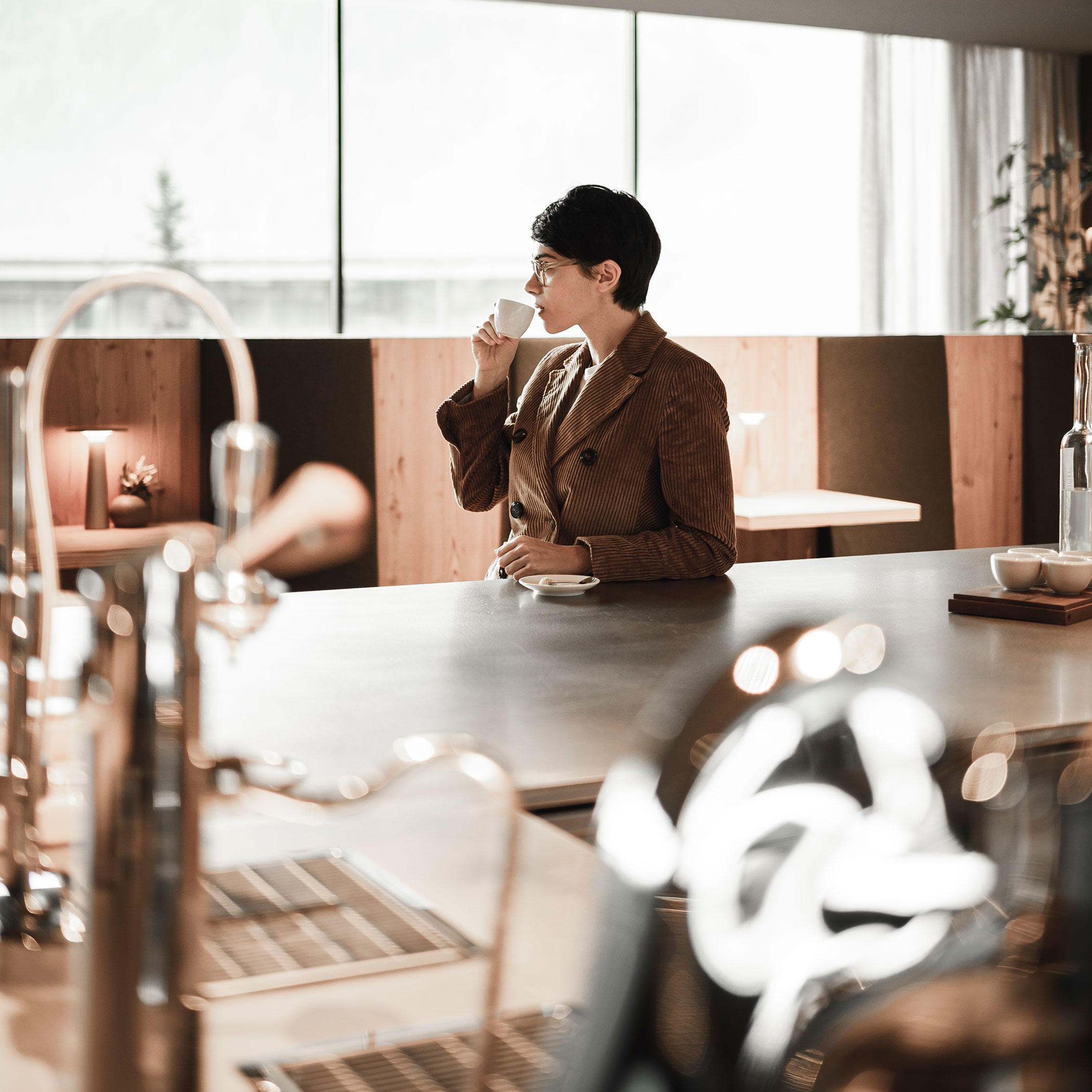 Eine Frau lehnt an der Bar und trinkt einen Kaffee - OLM Nature Escape
