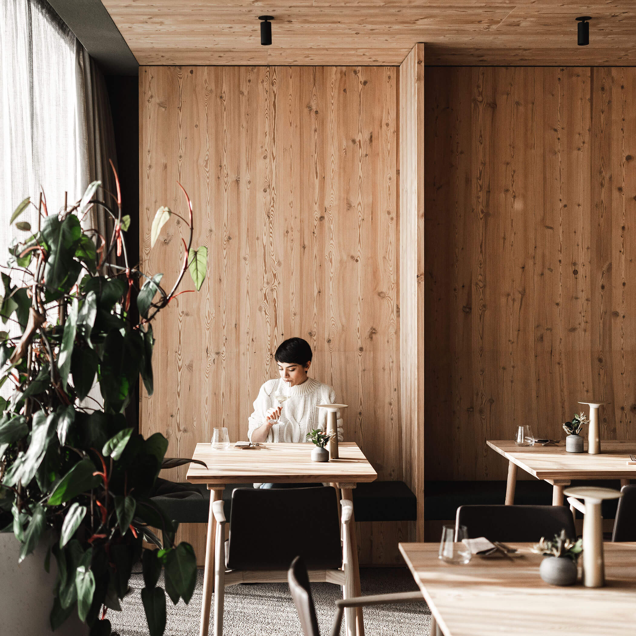 Frau sitzt mit Weinglas an einem Tisch im Restaurant - OLM Nature Escape