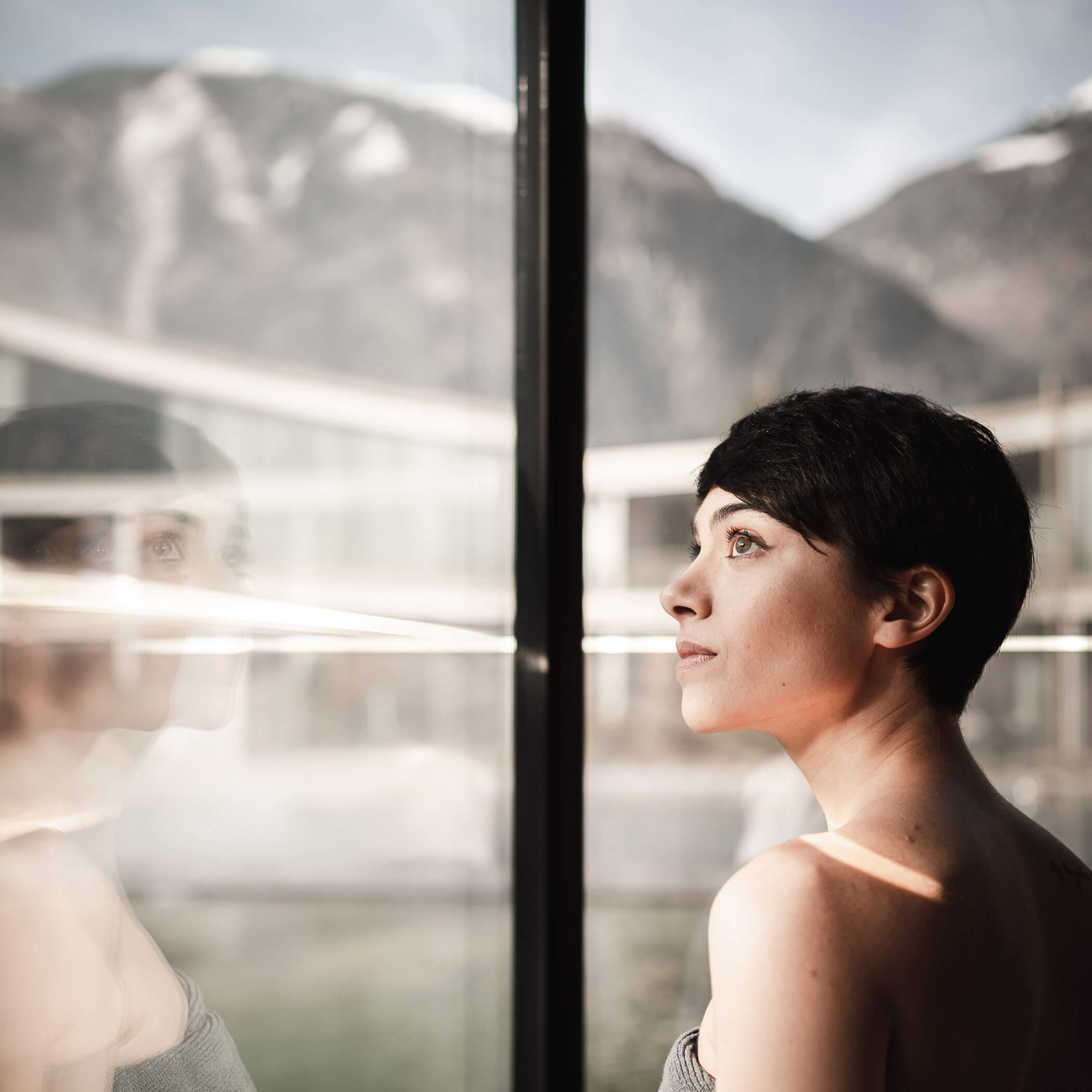 Woman looking out of the sauna into the courtyard - OLM Nature Escape