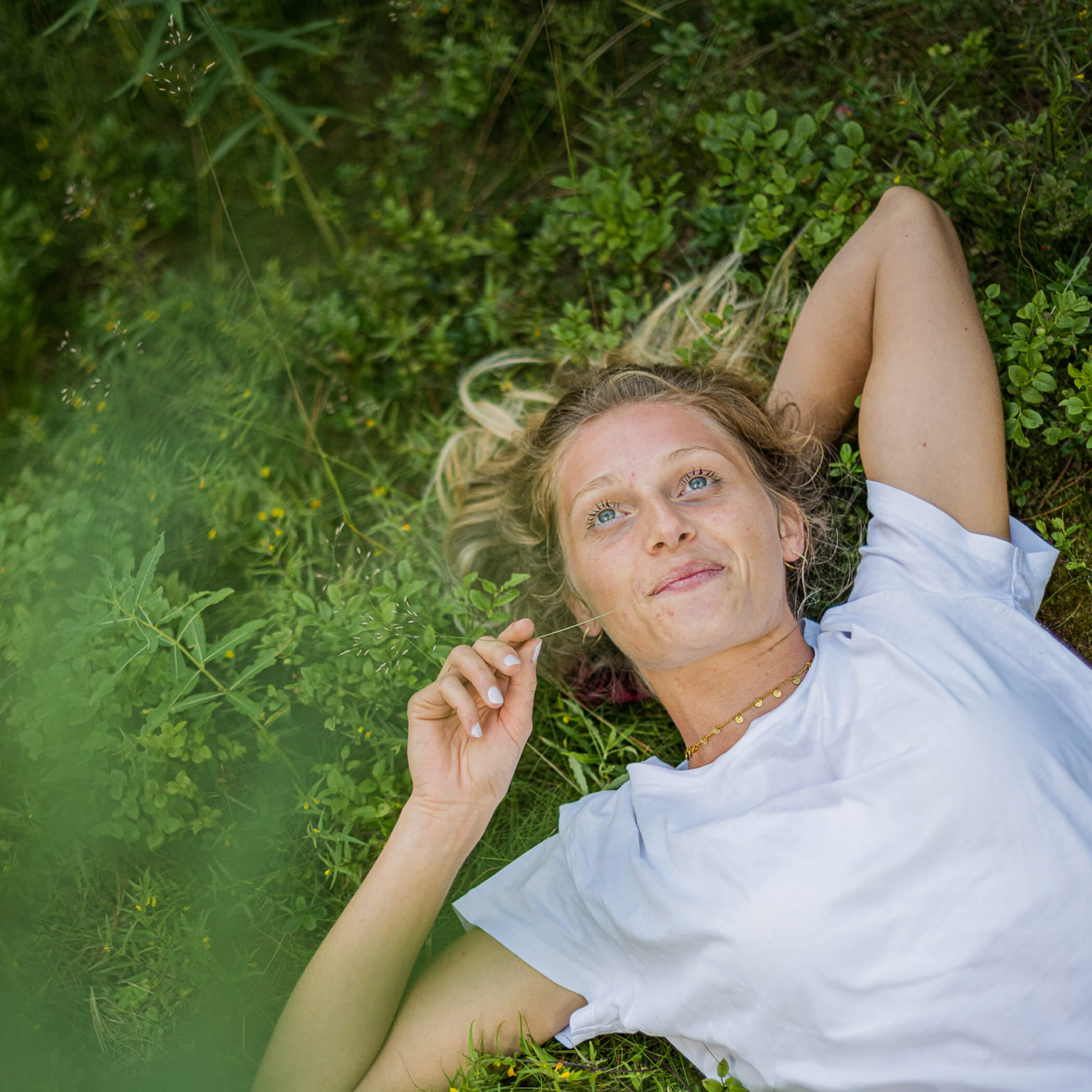 Frau liegt in der Wiese und schaut in den Himmel - OLM Nature Escape